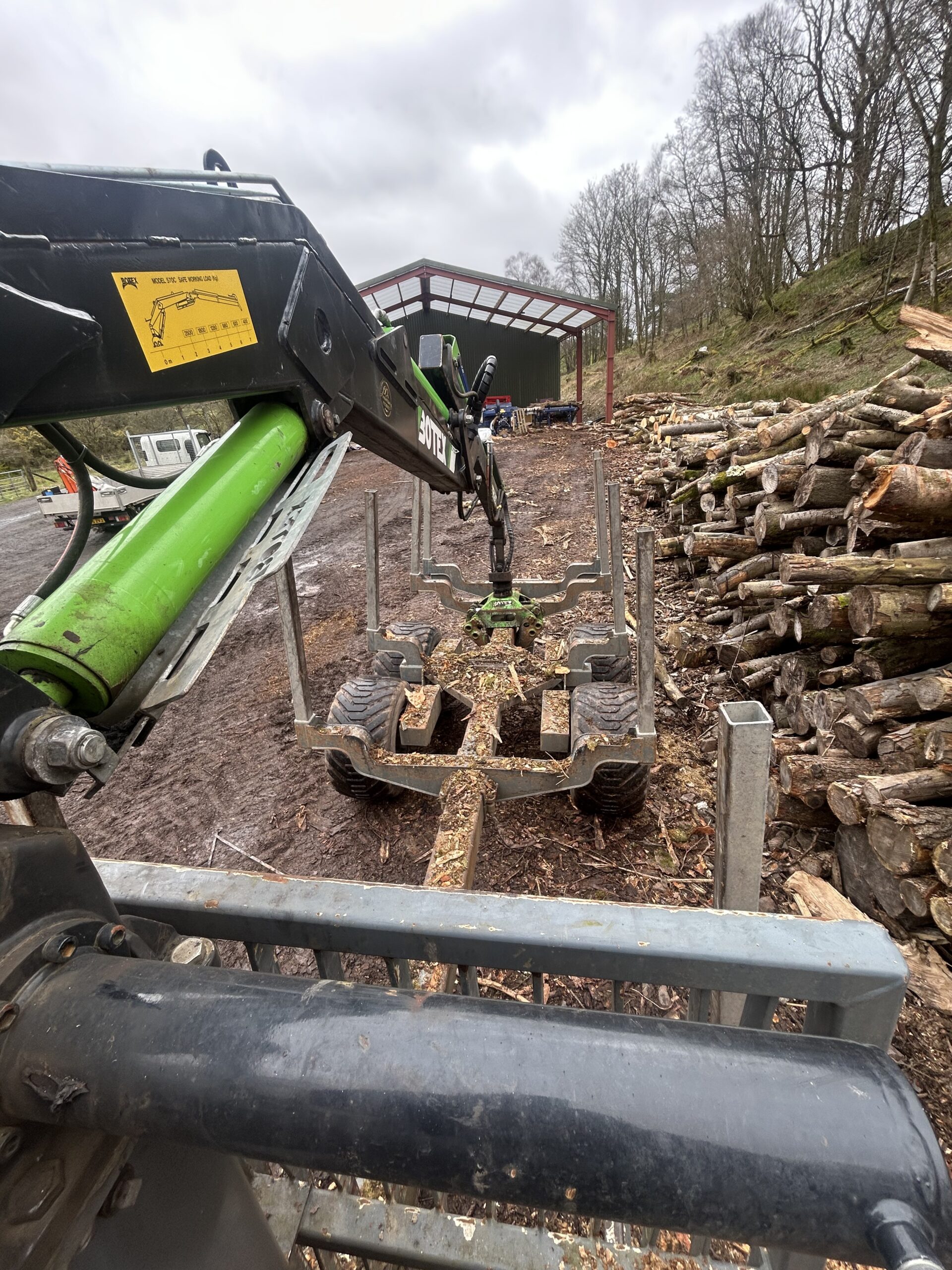 A forestry grapple loading logs onto a timber trailer.